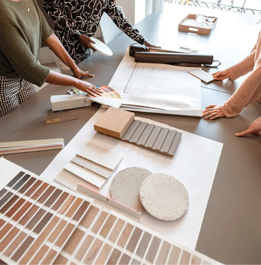 Beratungssituation am Tisch mit Farb- und Materialmustern, Holzproben und Planungsunterlagen für Raumgestaltung und Innenarchitektur, moderne Wohnberatung und Einrichtungskonzept.